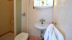 Une salle de bain avec des toilettes, un lavabo et une douche.