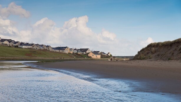 A beach with houses in the background. - Bwthyn Siwan: Charming Pet-Friendly Cottage in Aberffraw | Managed by Anglesey Holiday Lettings (Ty Croes)
