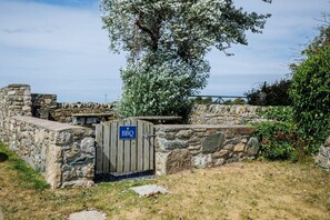 A stone wall with a wooden gate labeled 'BBQ' and a picnic table. - Bwthyn Siwan: Two bedroom, pet-friendly holiday cottage (Ty Croes)