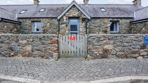 A stone building with a wooden gate, a small window, and a sign indicating private access. - Bwthyn Siwan: Charming Pet-Friendly Cottage in Aberffraw | Managed by Anglesey Holiday Lettings (Ty Croes)