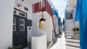 A narrow street with white buildings, red railings, and a blue staircase.