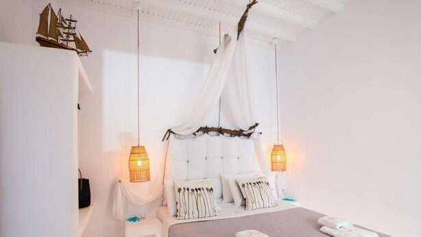 A bedroom with a canopy bed, white walls, and two bedside lamps.