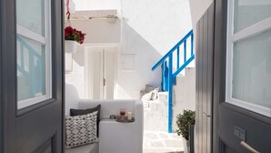 A narrow hallway with a blue staircase leading to a door marked "HOUSE 2".