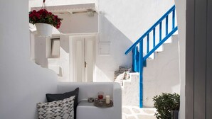 A narrow corridor with a white wall, a blue staircase, and a hanging flower pot.