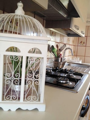 Una cocina con estufa a gas, un adorno blanco y salpicadero de azulejos.
