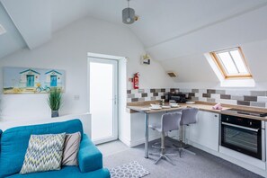Une cuisine compacte avec un coin repas, un canapé bleu et un tableau accroché au mur.