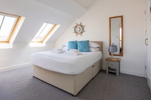 Une chambre à coucher avec un lit, des fenêtres de toit, une table de chevet, un miroir et un élément décoratif mural.