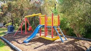 Un parque infantil con tobogán, estructura de escalada y columpios.