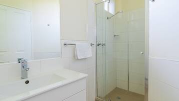 A bathroom with a white sink, mirror, and glass shower enclosure.