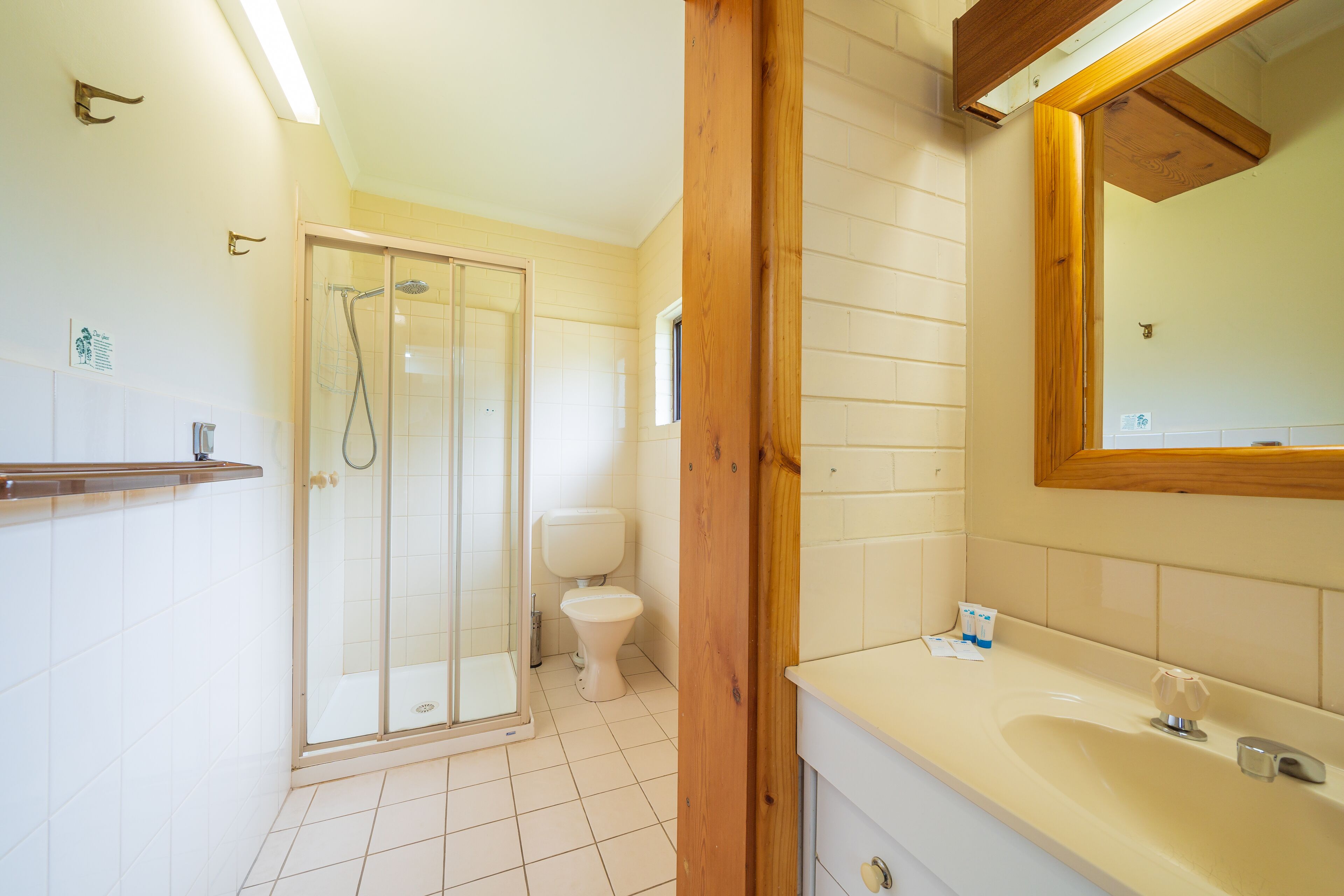 Un baño con cabina de ducha de vidrio, inodoro y lavamanos con espejo.