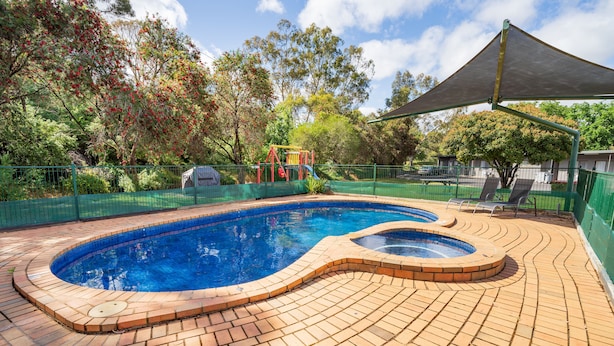 Piscina con suelo de ladrillo y zona sombreada.