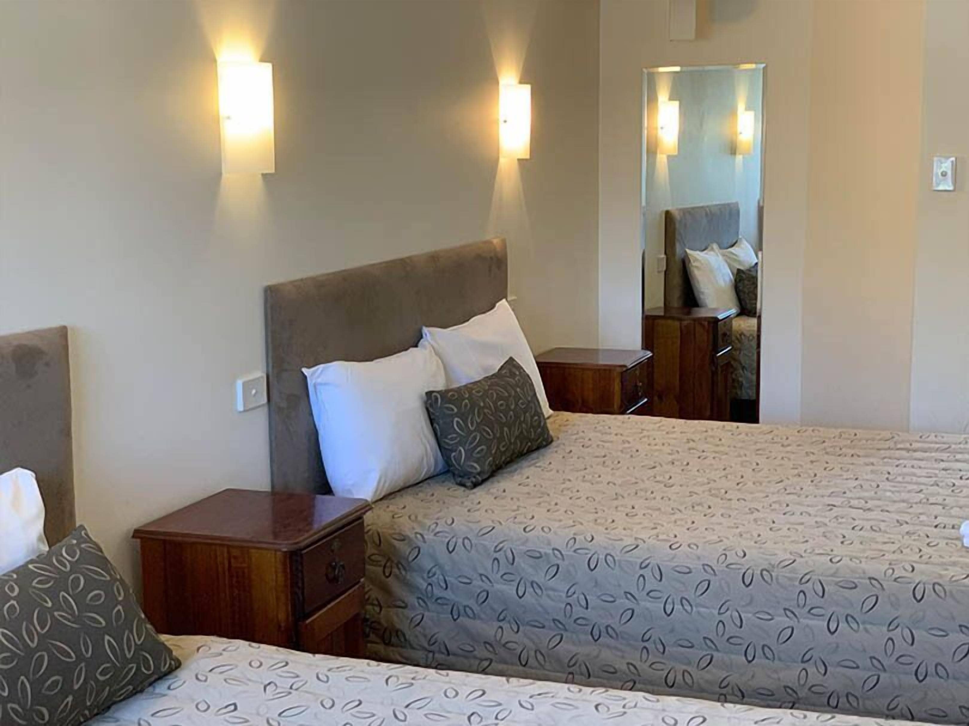 A hotel room with a large bed, two bedside tables, and wall-mounted lights.
