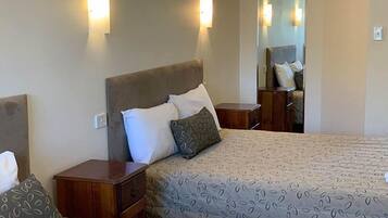 A hotel room with a large bed, two bedside tables, and wall-mounted lights.