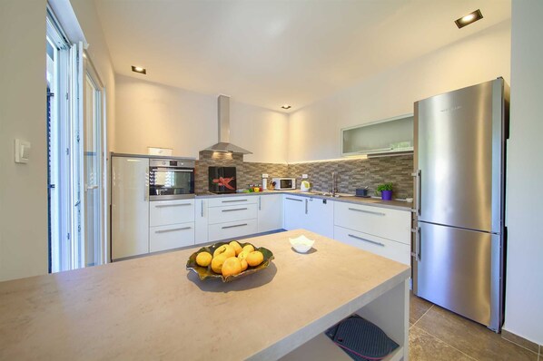 A modern kitchen with a built-in oven, microwave, and stainless steel refrigerator.