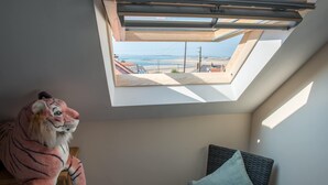 Ein Zimmer mit Oberlichter, einer Tiger-Kuscheltier und einem Bett mit Kissen.