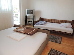 A room with two beds, a television on a stand, and a window with curtains. - Apartment Dragica 1  with terrace (Malinska)