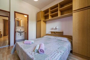 Un dormitorio con cama, armario de madera, espejo y baño con lavamanos.