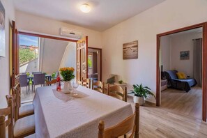Un comedor con una mesa dispuesta para dos, una planta en maceta y vistas del patio exterior.