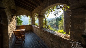 A stone-walled terrace with a wooden table and chairs, offering a view of a mountainous landscape. - 15th century castle, between Cinque Terre and Portofino, private pool, sea view (Leivi)