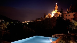 A swimming pool at night with a lit-up building in the background. - 15th century castle, between Cinque Terre and Portofino, private pool, sea view (Leivi)
