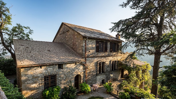 A stone building with a sloped roof, arched windows, and a small garden area. - 15th century castle, between Cinque Terre and Portofino, private pool, sea view (Leivi)