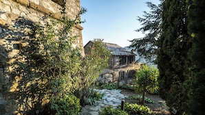 A stone building with a rustic exterior, surrounded by lush greenery and a stone pathway leading to a wooden structure. - 15th century castle, between Cinque Terre and Portofino, private pool, sea view (Leivi)