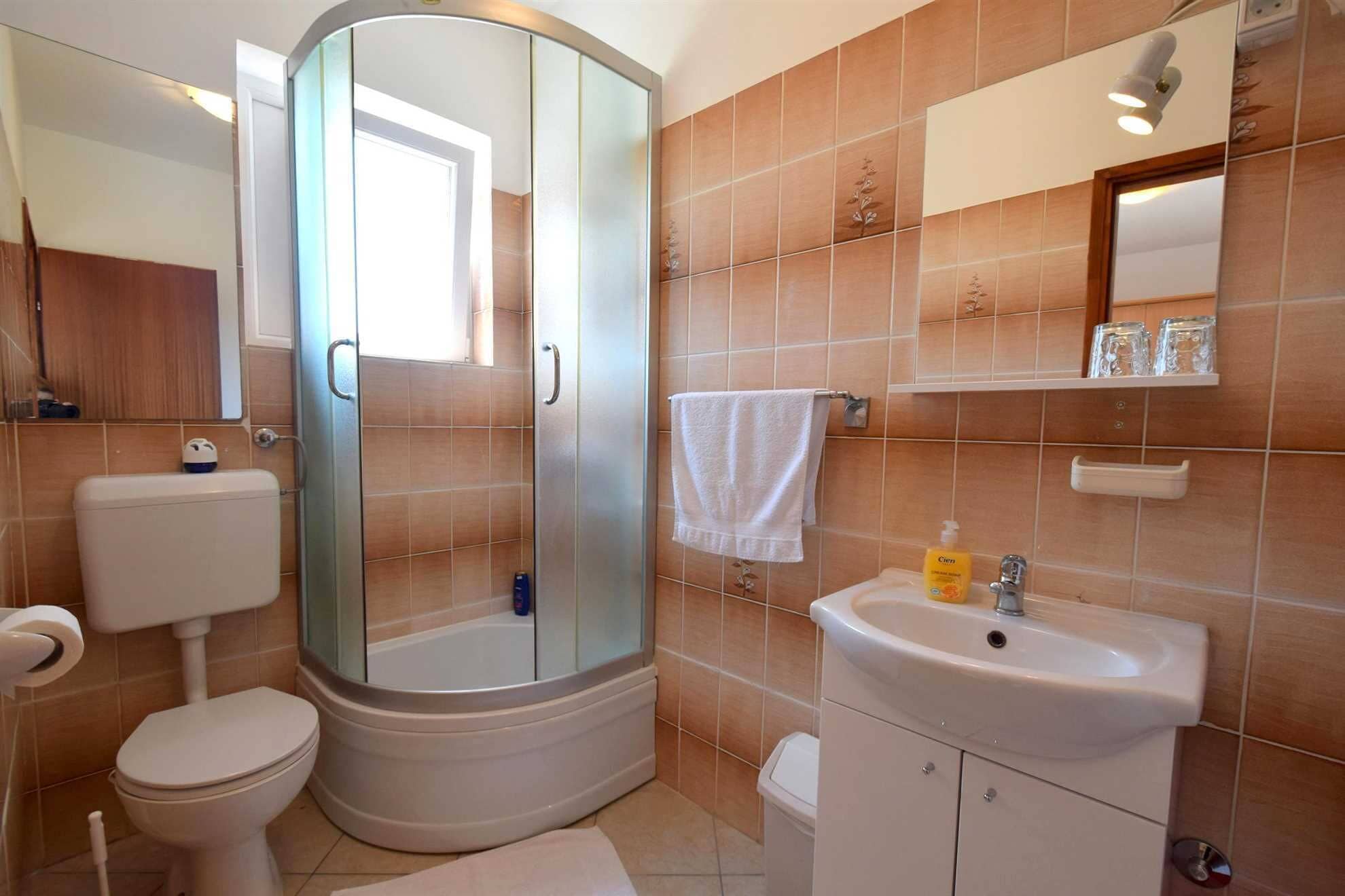 Een badkamer met een douchecabine, een toilet, een wastafel en een spiegel boven de wastafel.