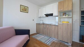 A compact living space with a kitchenette, a sofa, and a small rug. - Apartment Frane 2 with Seaview (Vantačići)