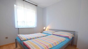 A small, bright bedroom with a single bed, a window with sheer curtains, and a bedside lamp. - Apartment Frane 2 with Seaview (Vantačići)