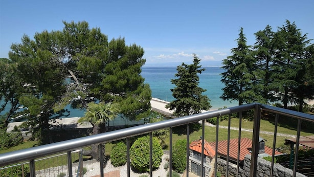 A balcony with a metal railing overlooking a coastal area with trees and a view of the sea. - Apartment Frane 2 with Seaview (Vantačići)