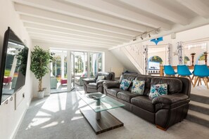 A modern living room with a glass coffee table, leather sofa, and a TV.