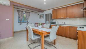 A compact kitchen with wooden cabinets, a built-in microwave, and a stainless steel refrigerator.