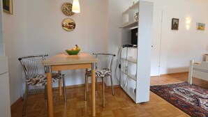En kompakt bolig med spiseplads, tekøkken og et lille soveværelse.