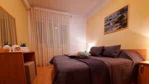 Een slaapkamer met een bed, nachtkastje, bureau en een schilderij aan de muur.