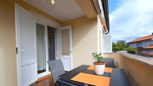 Un balcon avec une table, des chaises et un pot de fleurs.