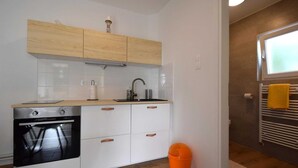 Une cuisine moderne avec des meubles blancs, un four encastré et un évier.