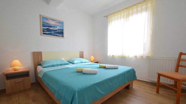 Une chambre bien rangée, avec un lit, des lampes de chevet, une chaise et une fenêtre avec des rideaux.