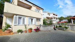 Un bâtiment à deux étages doté d’un balcon, de plantes en pot et d’une allée pavée.