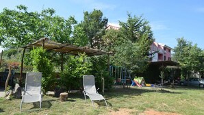 En have med to liggestole, en træpergola og en legeplads med rutsjebane.