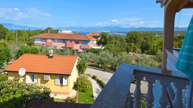 A residential area with houses and a clear view of the sea and mountains in the background.