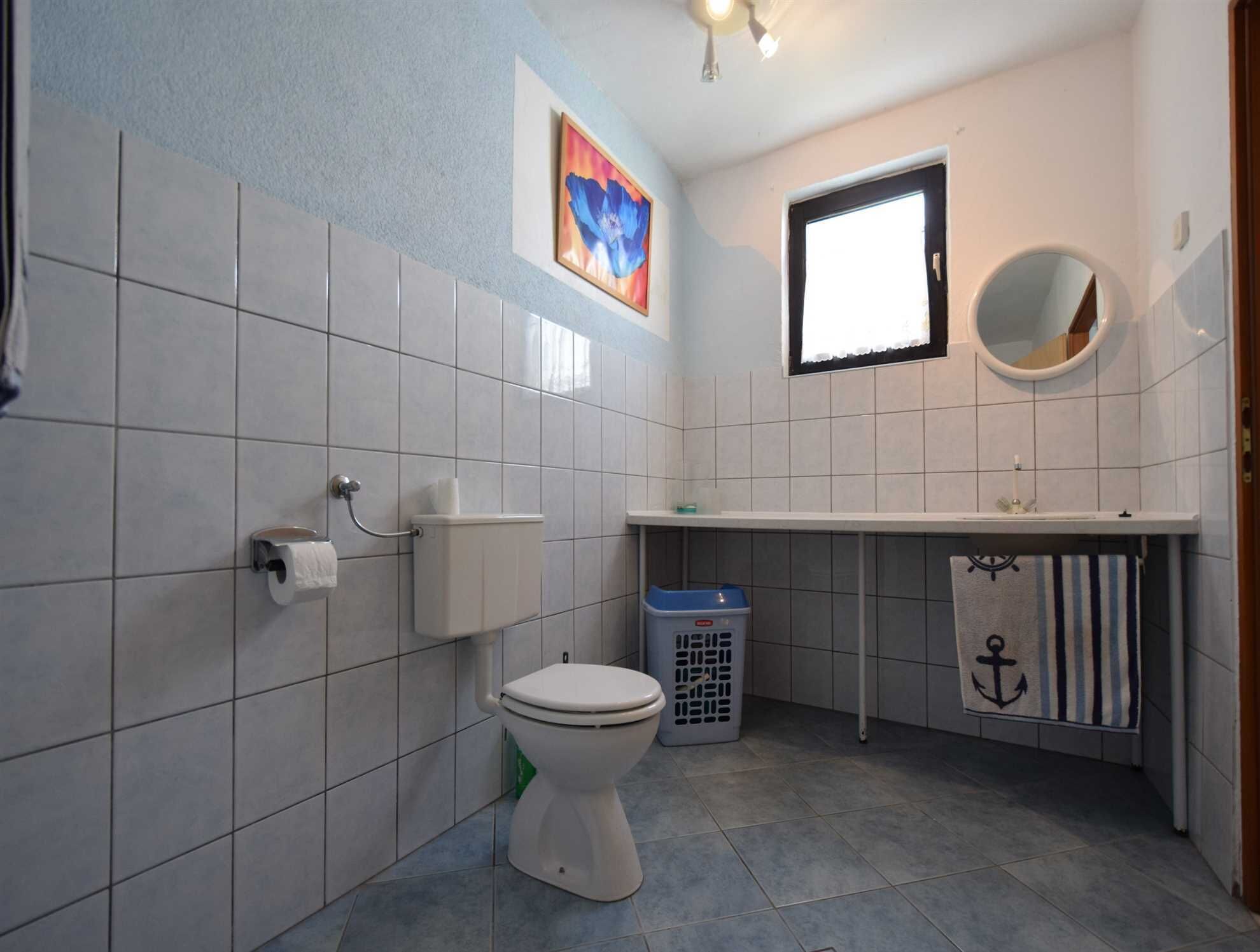 A bathroom with a toilet, sink, and a window.