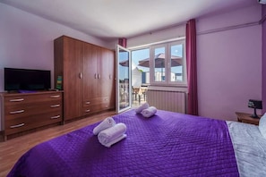 Ein Schlafzimmer mit Bett, Kleiderschrank, Fernseher und einem Fenster mit Blick.