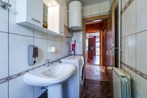 Ein Badezimmer mit Waschbecken, Waschmaschine und Spiegel.
