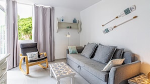 Una sala de estar moderna con un sofá gris, una mecedora y una mesa de centro con estampado.