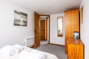 A bedroom with a bed, a wooden wardrobe, a mirror, and a painting on the wall. - Y Stabl: Pet-friendly cottage with stunning views (Ty Cros)