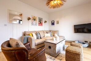 Ein Wohnzimmer mit einer Couch, einem Couchtisch, einem Ledersessel und einem Fernseher.