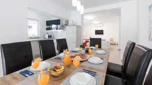 Un comedor moderno con una mesa de madera preparada para el desayuno, que incluye jugo de naranja y fruta.