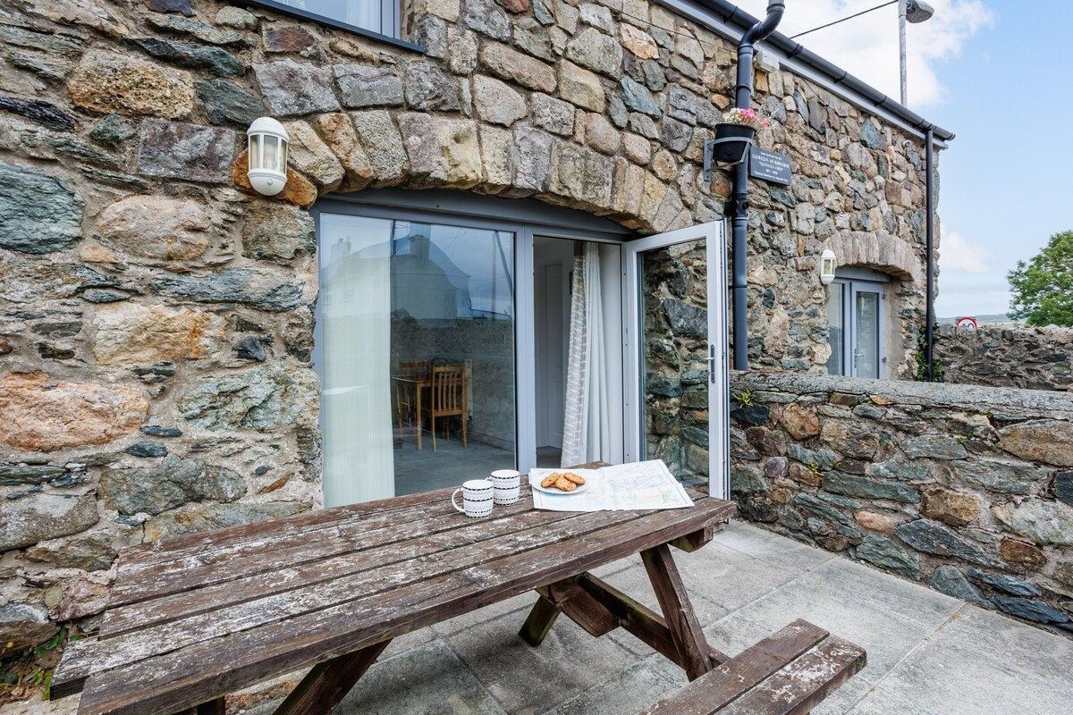 A stone building with a wooden bench outside, a door, and a window.