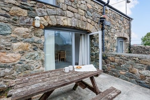 A stone building with a wooden bench outside, a door, and a window.