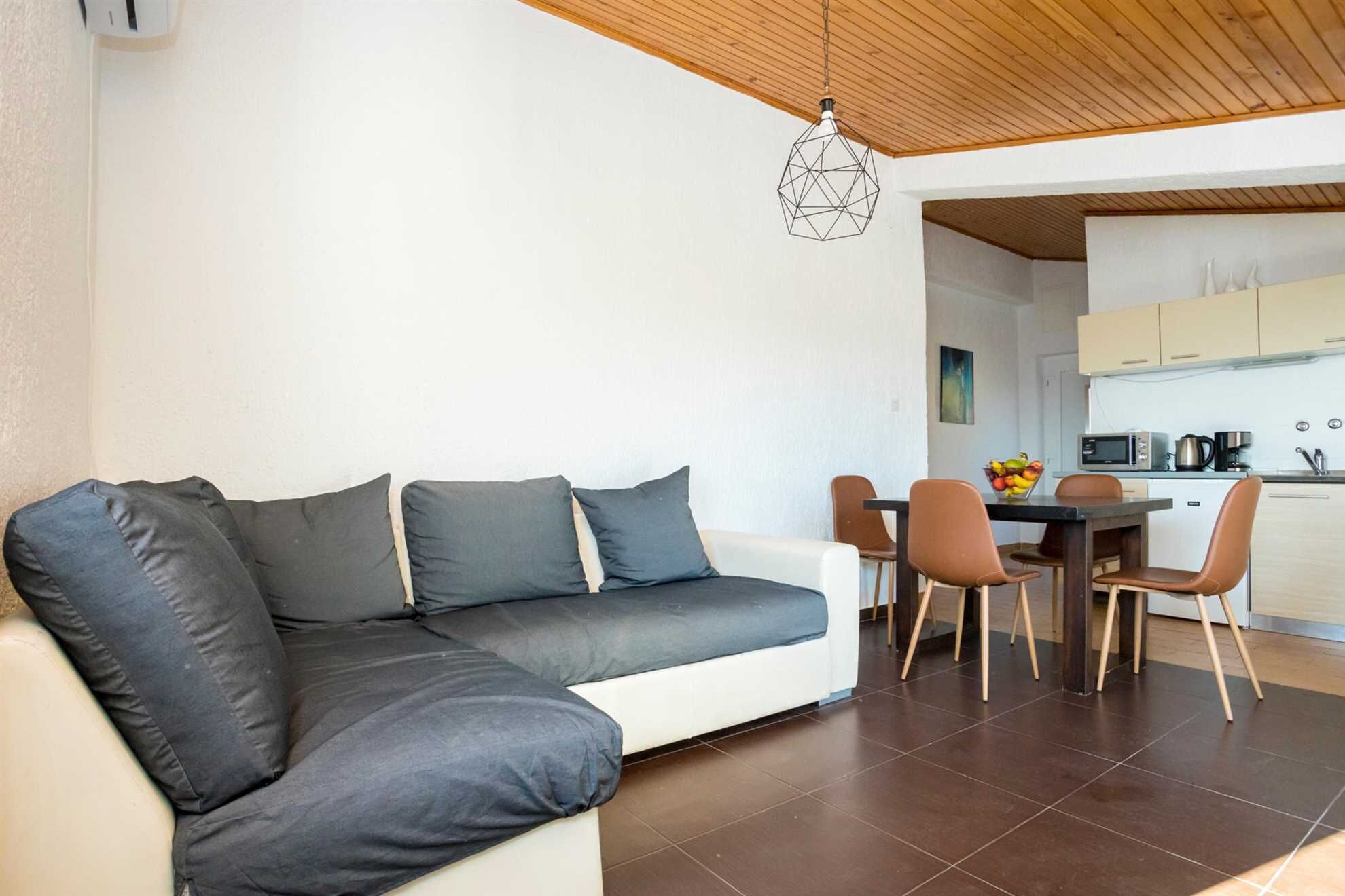 Una sala moderna con sofá, mesa de comedor y sillas. Una lámpara colgante de diseño geométrico cuelga del techo.
